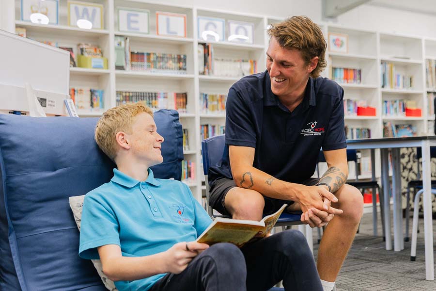 A student in the library engaged in a conversation with a teacher.