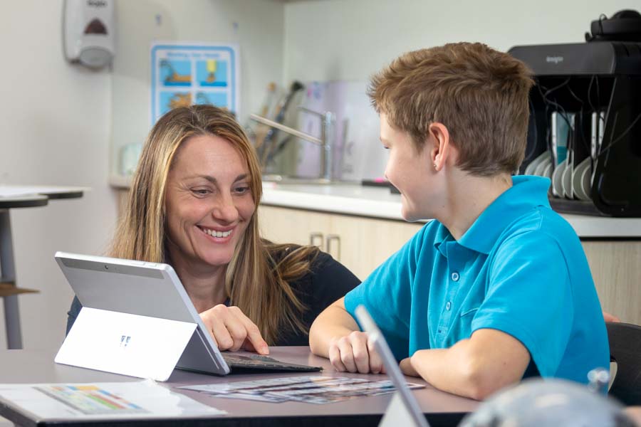 A teacher and student in their classroom, sharing smiles and positive interactions.