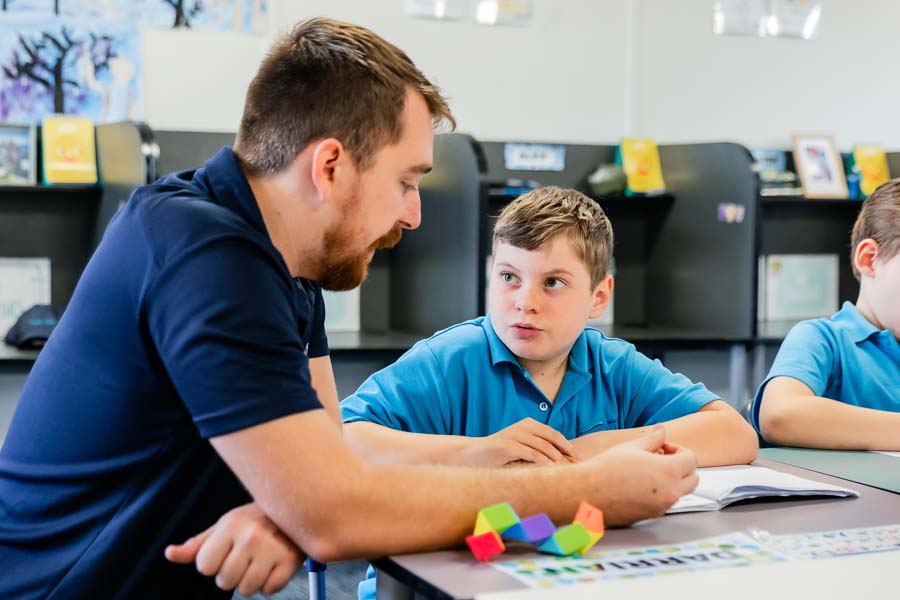 A Youth Support Worker providing support to a student in the classroom, fostering an inclusive and encouraging learning environment.